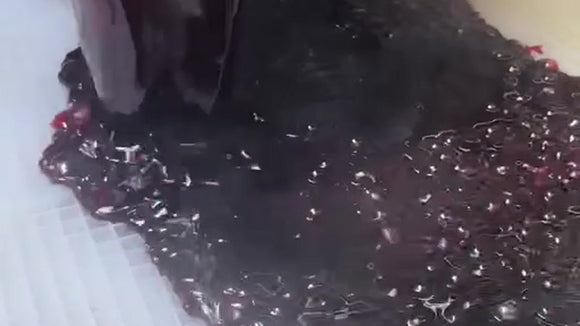 Purple gummy mixture poured across a commercial silicone mold during gummy production