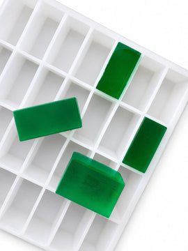 Angled view of a 20mL rectangle gummy mold with 119 cavities and translucent emerald green rectangular gummies