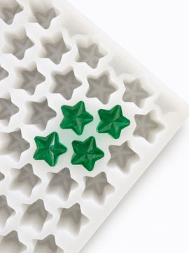 Angled view of a 4mL star gummy mold with 168 cavities and emerald green star gummies
