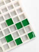 Top-angle view of a 6mL square gummy mold with 165 cavities and emerald green square gummies on a white background